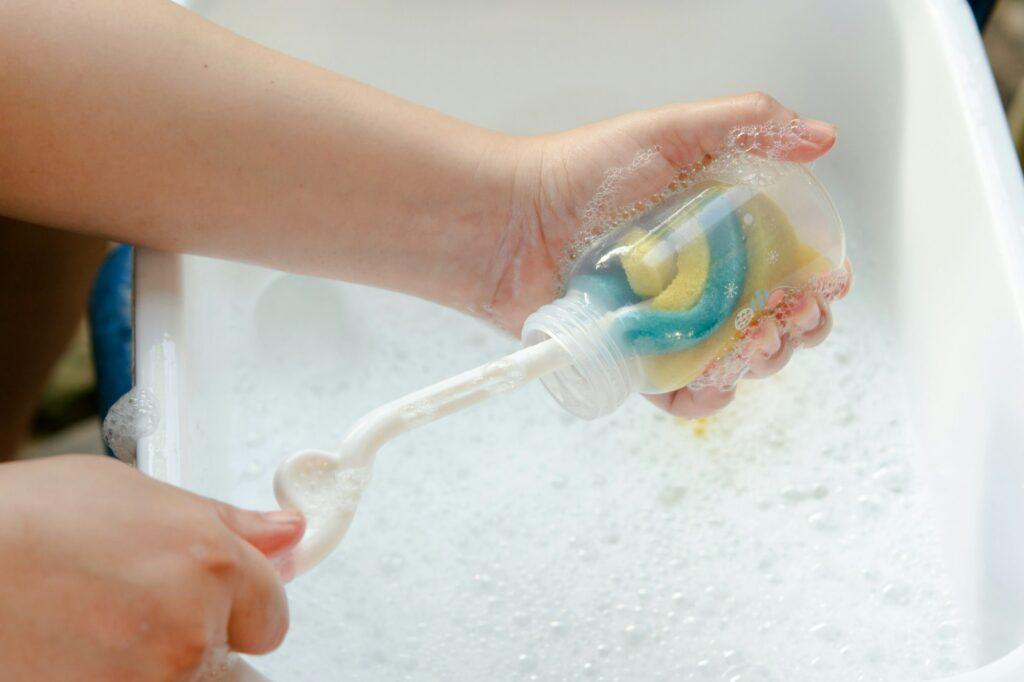 Washing baby bottle. Mother's hand washing the baby bottle