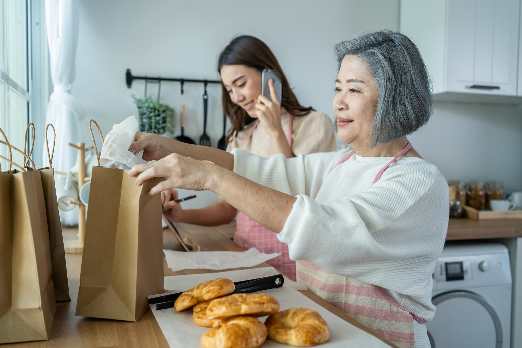 Asian happy family, senior mom and daughter cook food and sale at home.