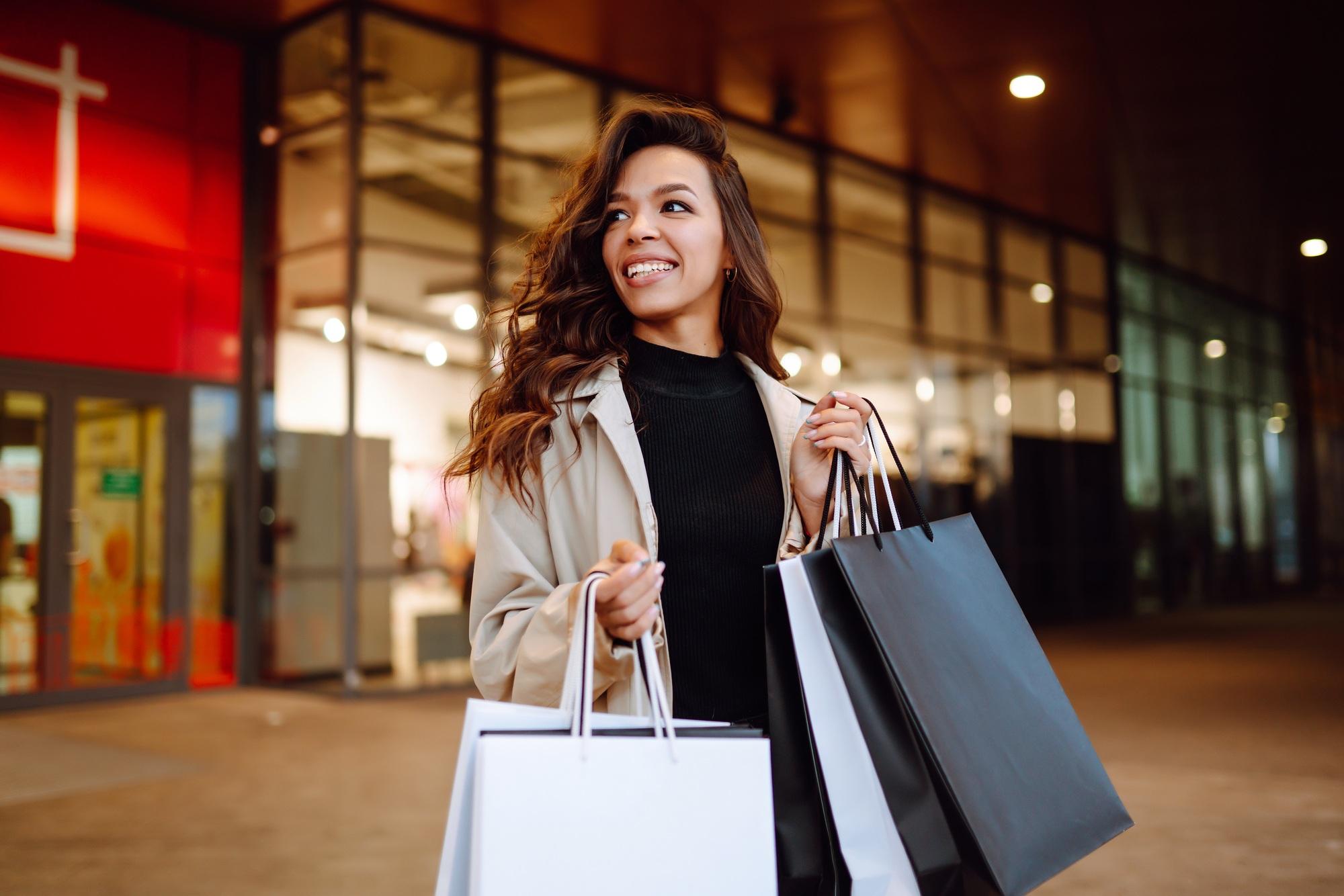 Young woman with shopping bags near mall. Spring Style. Consumerism, purchases, shopping, lifestyle.