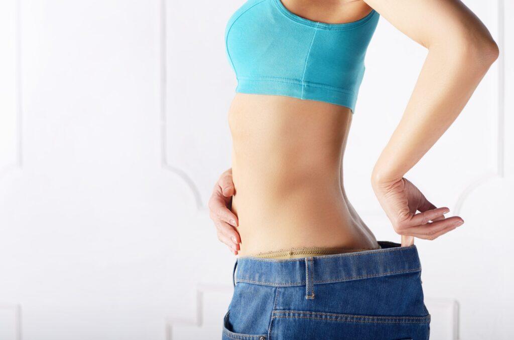 Caucasian female model in blue jeans showing her flat stomach. W