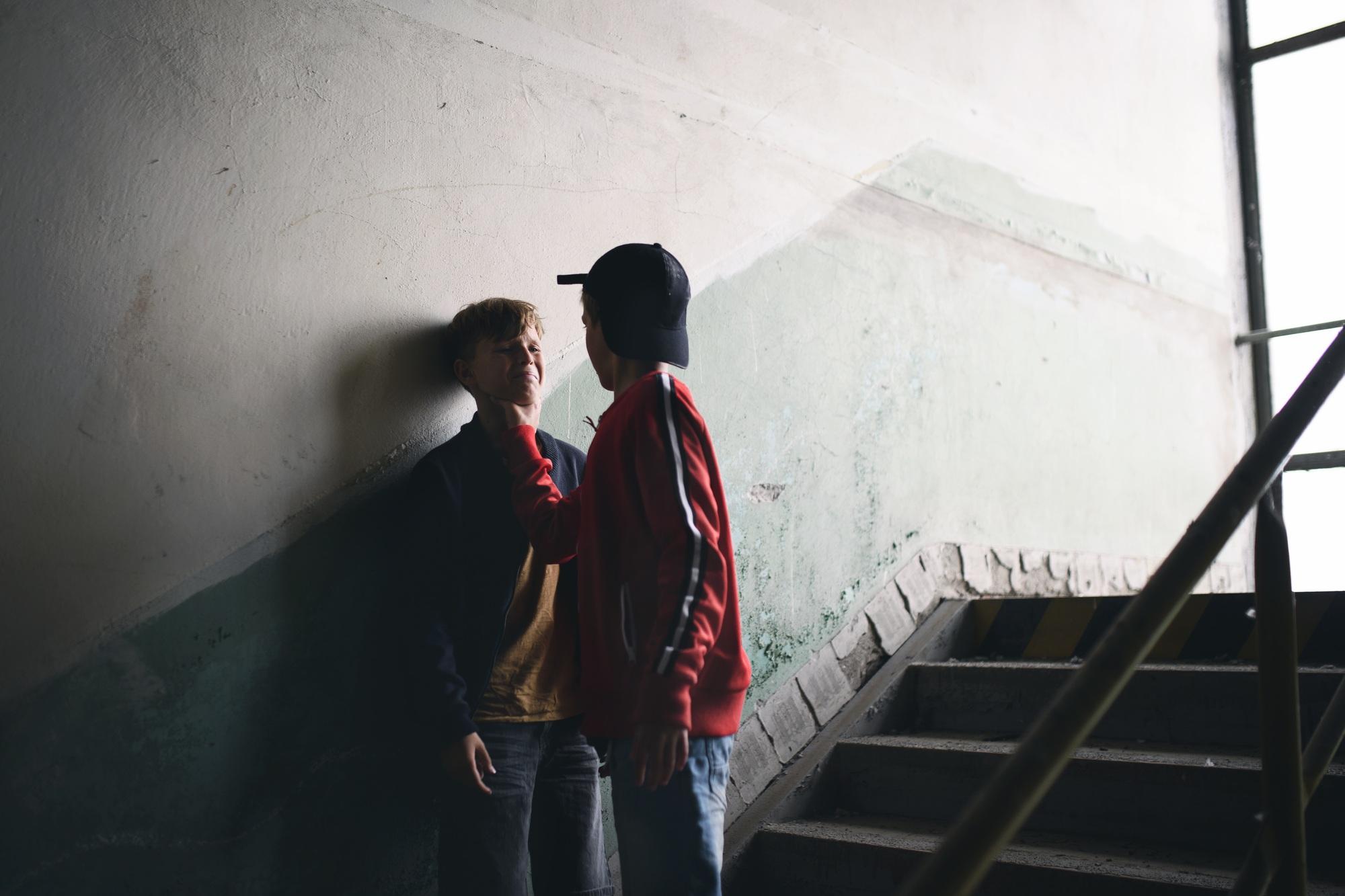 Teenage boy attacked by thug in abandoned building, gang violence and bullying concept.