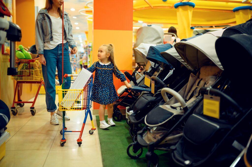 Mother and little girl buying baby stroller