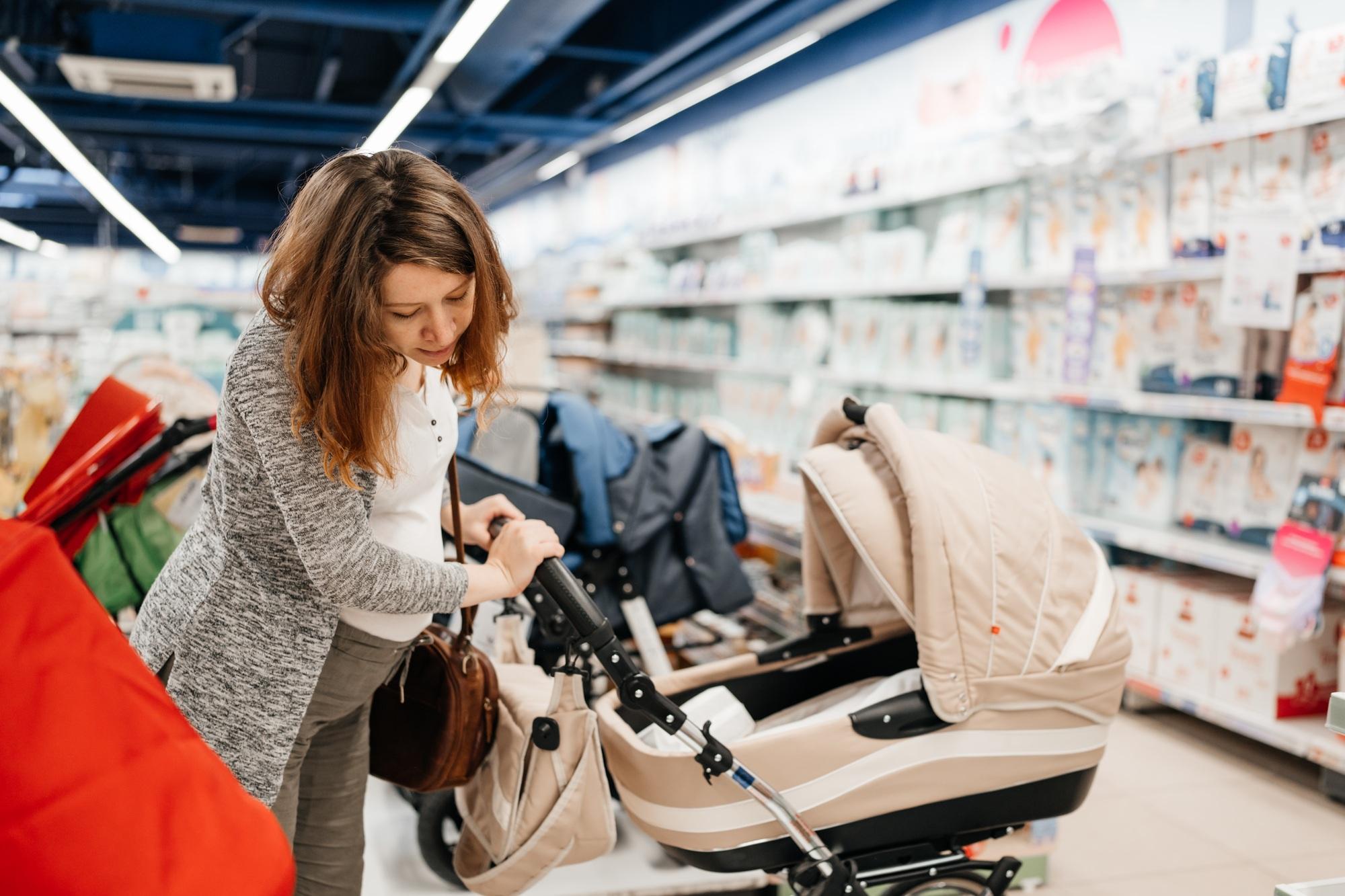 Pregnant woman choosing baby stroller in store.