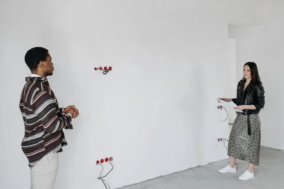 Étapes du couple : 12 moments qui comptent, du premier rendez-vous au projet commun A couple discussing property plans in a minimalist, empty room.