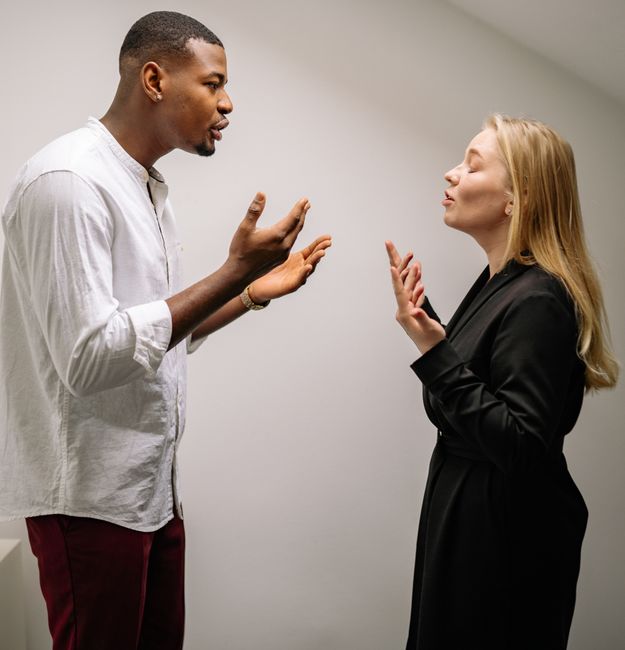 A couple engaged in a heated argument indoors, expressing strong emotions and gestures.