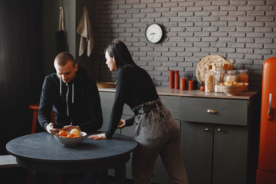 A couple having a conversation in a stylish kitchen, with a casual and relaxed atmosphere.