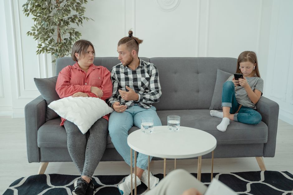 Couple et parentalité : 69 études sur l’attachement, 29 sur le stress A family therapy session with parents discussing things while a child is absorbed in her smartphone.