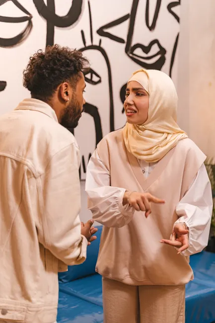 A man and a woman in a hijab having a serious conversation in a modern setting.