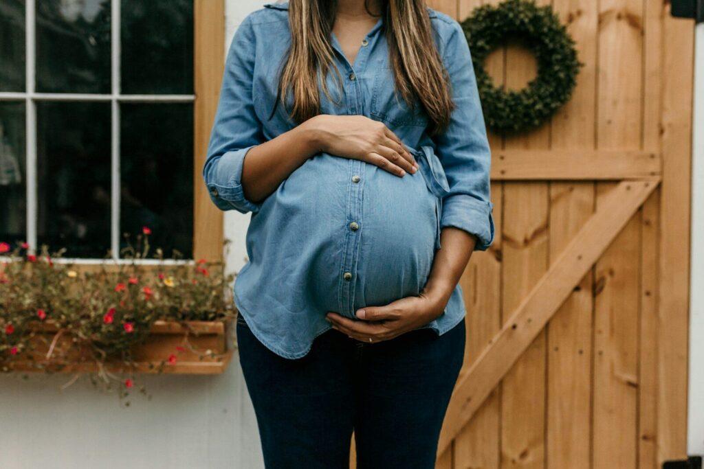 Taxi pour femme enceinte à Lille : le réflexe simple qui évite de payer trop cher woman in blue denim button up jacket and blue denim jeans standing near brown wooden fence