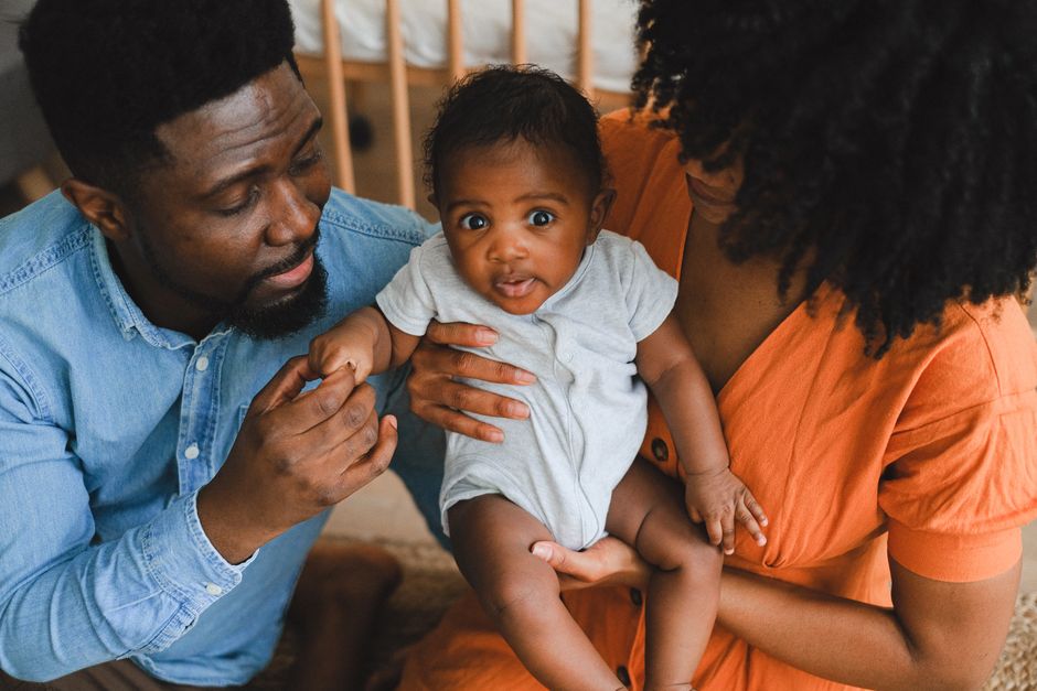 Après bébé, le couple tient-il le choc? 5 repères jusqu’à 2 ans Loving parents holding adorable baby in a warm, intimate home environment.