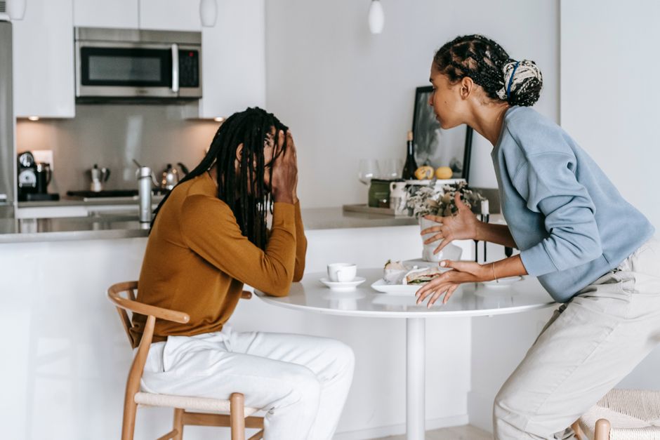 Satisfaction conjugale : 4 études, 3 ans et pas de gène magique Young black man sitting at table with hands on head and having conflict with standing near table woman in light kitchen