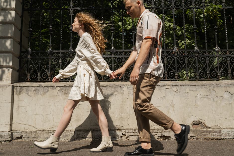 Amour romantique : 808 jeunes adultes, et les clichés prennent un râteau Young couple holding hands while walking on a sunny day, capturing a moment of togetherness.