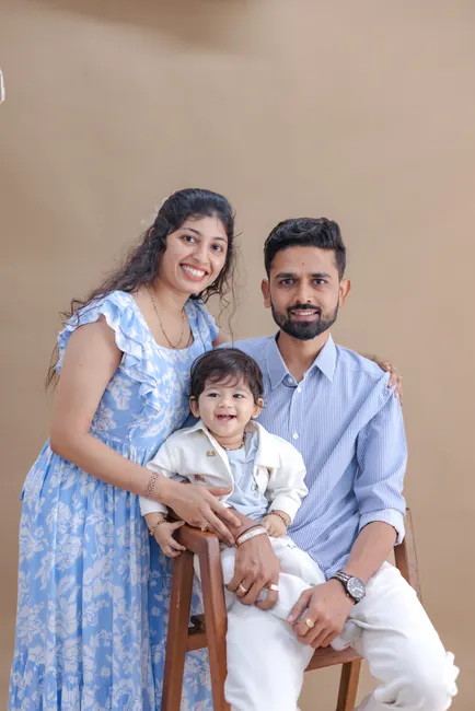 A cheerful studio portrait of a family with parents and a toddler, all smiling.