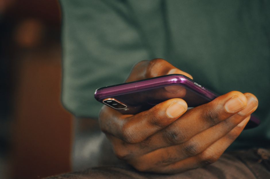 Amour non réciproque : 5 repères pour avancer quand le cœur s’entête A close-up shot of a person holding a purple smartphone indoors, focusing on texting or browsing.