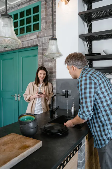 A couple chatting while washing dishes in a stylish kitchen setting.