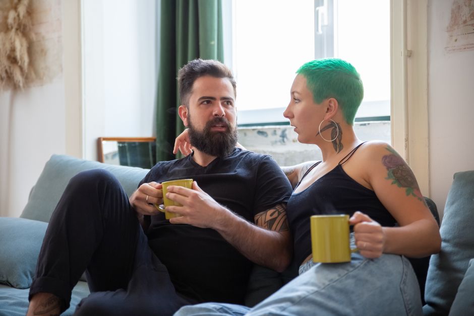 A couple enjoying a relaxed moment on their sofa with coffee at home.