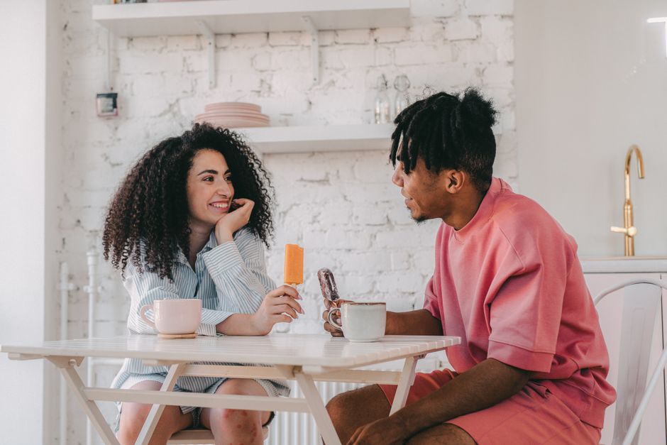 Black Love : 5 repères pour aimer sans s’effacer A couple enjoys a relaxed morning with coffee in a cozy kitchen setting, sharing smiles and popsicles.