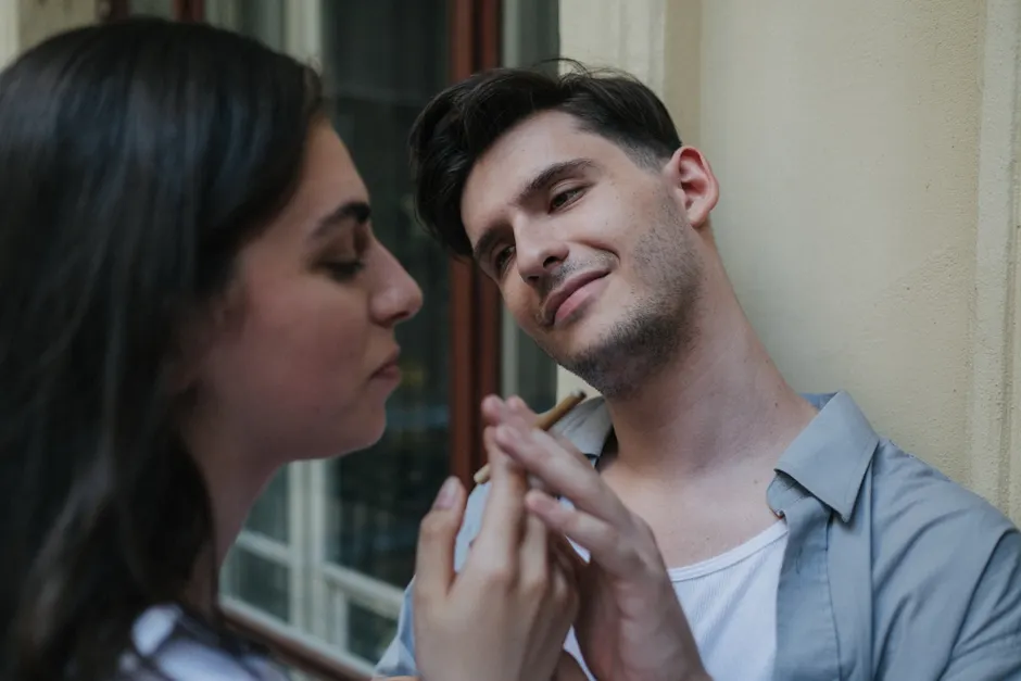 A couple enjoys a smoking break, sharing a connection outdoors in a calm setting.