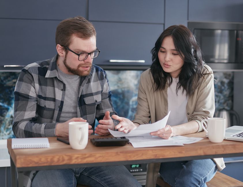 Théorie de l’échange social en couple : 5 repères pour sortir des comptes A couple having a serious discussion and reviewing documents at a kitchen table.
