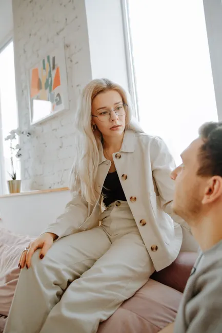 A couple having an earnest discussion in a cozy indoor setting. Warm tones and intimate atmosphere.