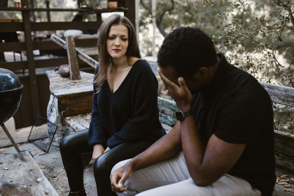 Masculinité dans le couple : 5 repères pour aimer sans dominer A couple having an emotional conversation outdoors, conveying sadness and concern.