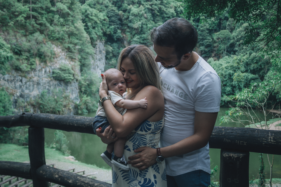 Couple après bébé : pourquoi 10 minutes de vrai temps comptent A family enjoys a tender moment outdoors by a cliffside, cuddling their baby in a serene natural setting.