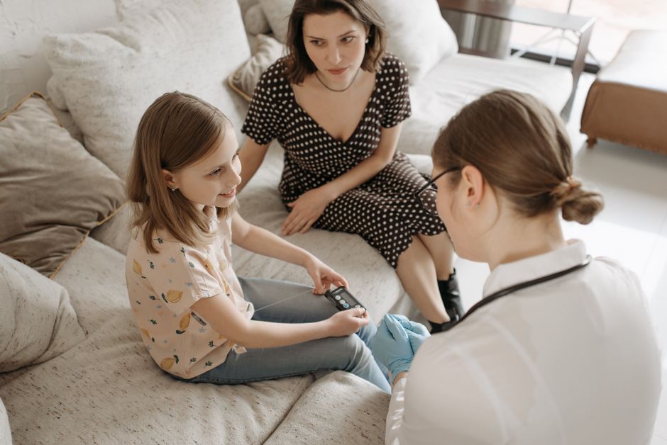 Lune de miel du diabète de type 1 chez l’enfant : des mois, parfois des années, mais pas de pause A healthcare provider assists a child with a diabetes check-up at home.