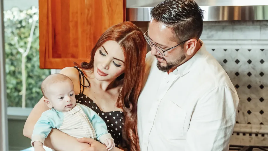 Après bébé, 7 petits gestes pour ne pas devenir colocataires A joyful family moment with parents and baby in a modern kitchen environment.
