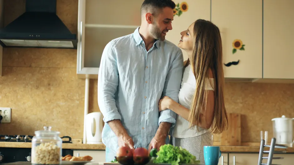 A loving couple shares a warm moment in a modern kitchen, showcasing a cozy and intimate lifestyle.