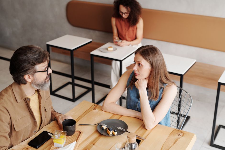 Consentement sexuel : 4 signaux chez les 18-26 ans, sans télépathie A man and woman engage in conversation over breakfast at a stylish coffee shop.