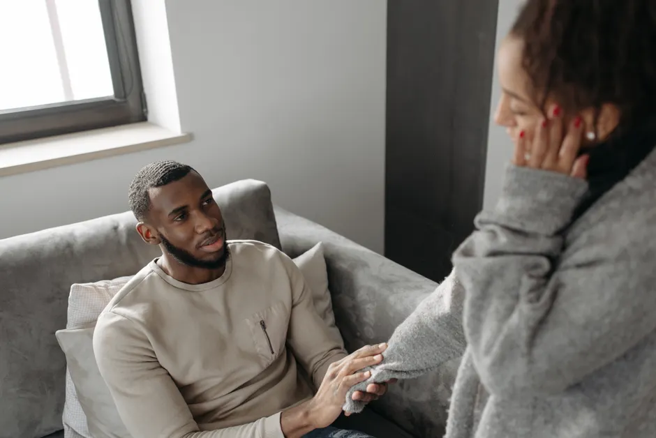 A man sitting on a sofa comforting a woman. Emotional support scene indoors.