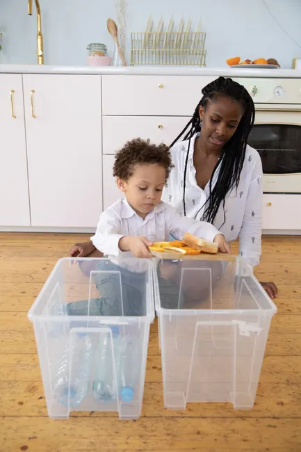 A mother and child sort recycling in a modern kitchen.
