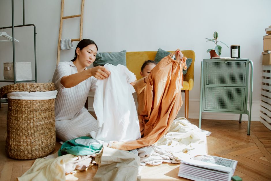 Qui vide le lave-vaisselle? 4 études sur le couple, sans procès A mother and daughter sort through clothes in a sunlit living room, creating a cozy family moment.