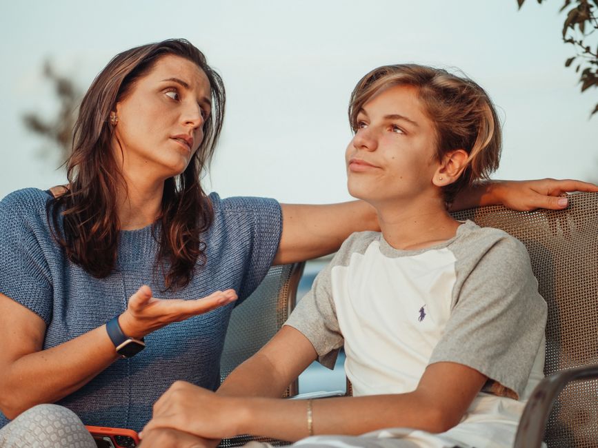 Violence dans le couple adolescent : 38 entretiens pour comprendre et prévenir A mother and her teenage son engage in a conversation sitting outside, expressing familial warmth and connection.