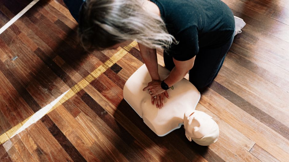 De 10 à 19 ans, les ados peuvent-ils transmettre les gestes qui sauvent? A person practices CPR on a training mannequin indoors.