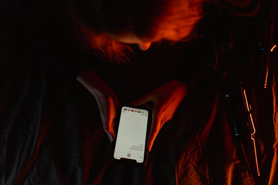 Smartphone : 3 études, 4 gestes pour reprendre la main A person using a smartphone in dim, moody lighting with a dark background.