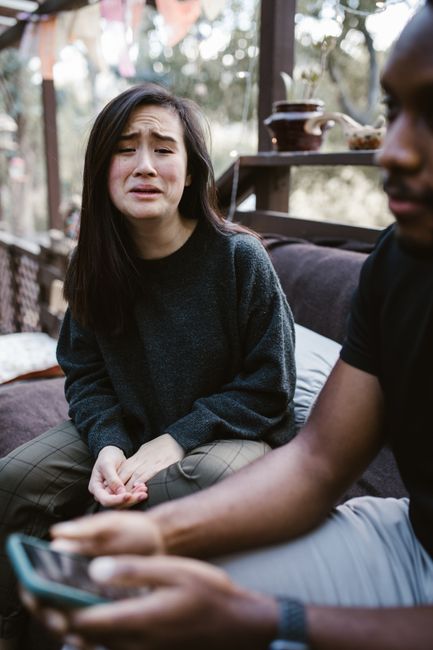 A woman in distress talks to a friend outdoors, showing strong emotions.