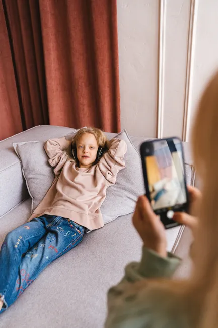 A young child enjoying music on headphones while being photographed indoors.