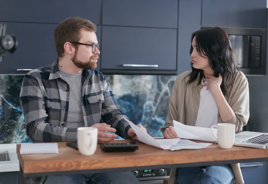 Langages de l’amour : 22 pays, zéro mode d’emploi universel A young couple sitting at a table discussing bills and financial plans in a modern kitchen.