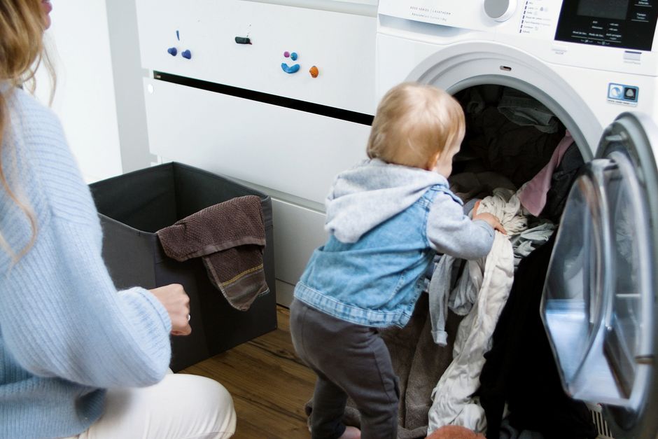 Après bébé : 5 gestes pour faire grandir son couple, sans mode d’emploi Adorable child assisting in laundry chores indoors with mother.