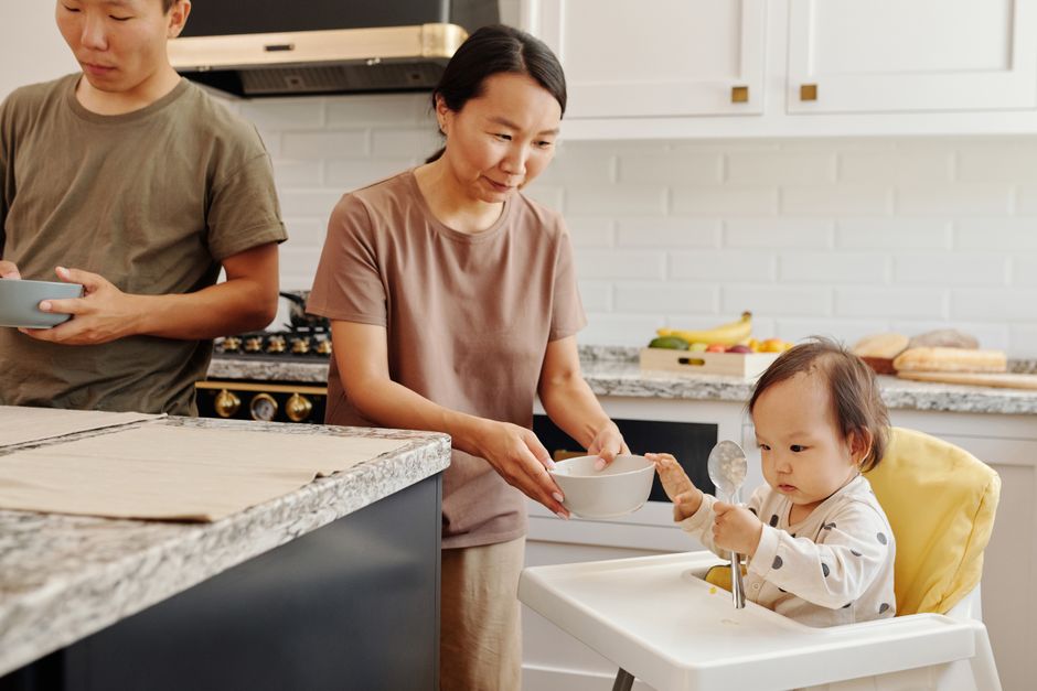 Couple après bébé: 52 semaines pour suivre le duo, sans mode d’emploi An Asian family with a baby enjoying meal time together in a stylish kitchen.