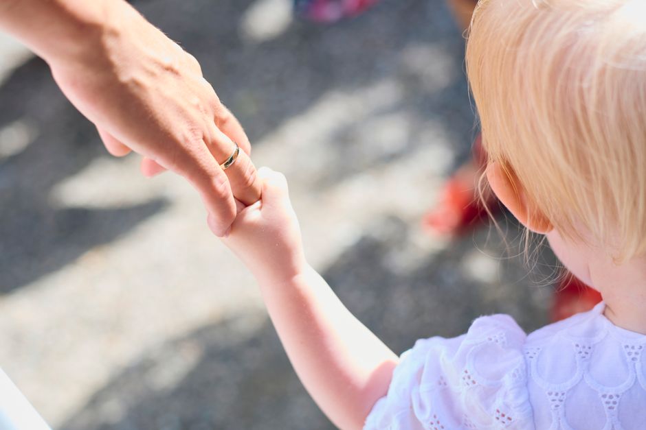 Relations saines : comment élargir son soutien sans s’épuiser Blonde child holding parent's hand outdoors, symbolizing love and protection.