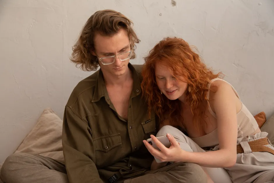 Mèmes de couple après bébé : 4 repères pour rire sans blesser Calm couple in casual clothes browsing smartphone and looking at screen while resting together in light room in apartment