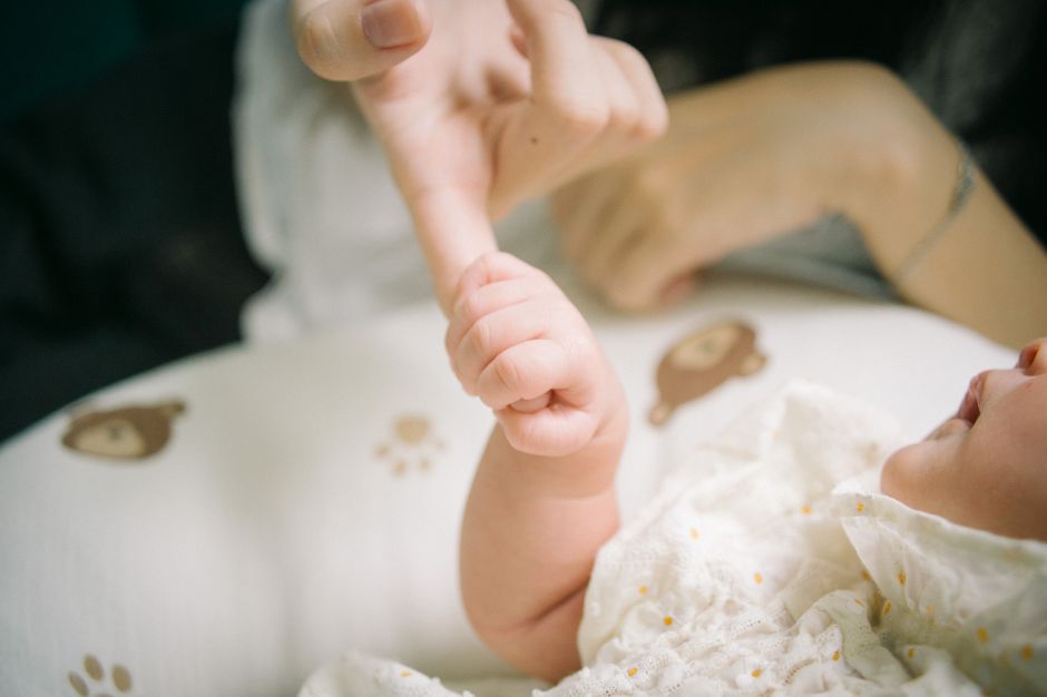 Après bébé, 5 gestes d’affection pour garder le lien Close-up of a baby holding a parent's finger, symbolizing care and connection.