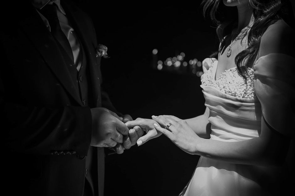 Mariage et santé mentale : 20 mois de suivi, la bague ne fait pas tout Close-up of a couple exchanging rings during a wedding ceremony, captured in black and white.