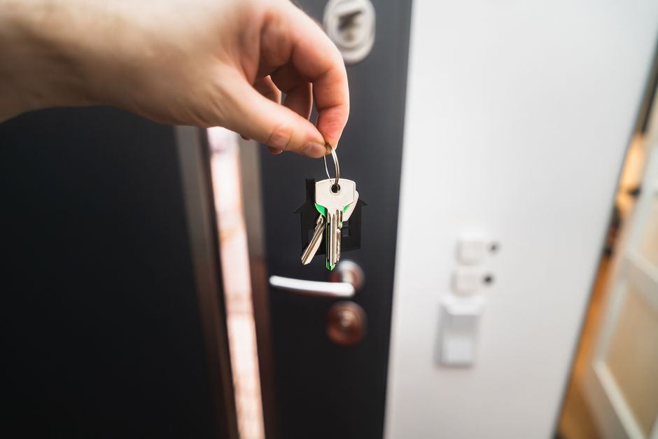 Croire encore en l’amour après une relation douloureuse : 4 repères sans conte de fées Close-up of a hand holding keys in front of an open door, symbolizing new homeownership.