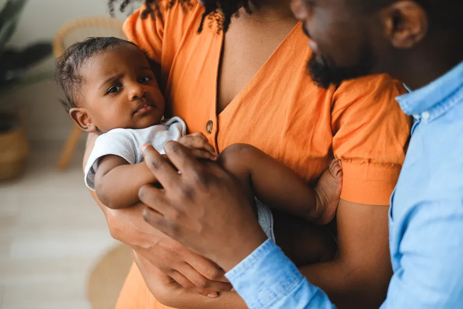 Couple après bébé: 5 repères pour les 12 mois qui tanguent Close-up of affectionate parents holding their baby indoors, highlighting a warm and intimate family connection.