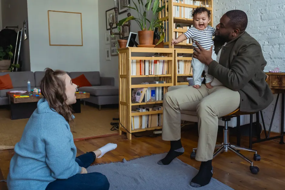 Réseau de soutien parental : 4 aides après bébé, fini le « dis-moi si besoin » Diverse family members spending time together at home with little kid and sitting on floor and holding baby on knees