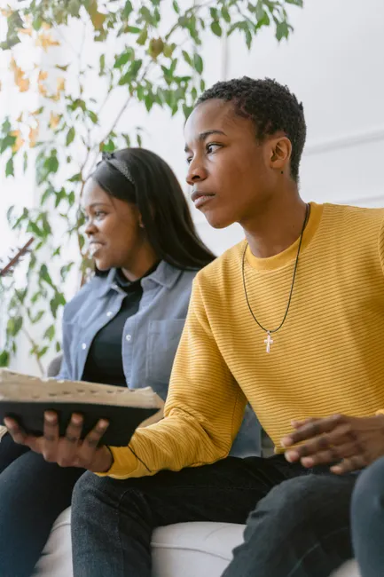 Focused young adults reading and discussing indoors with a relaxed atmosphere.