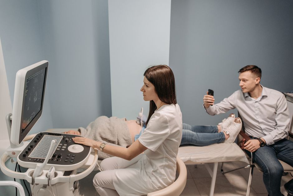 Medical professional conducts ultrasound for expectant couple in clinic.